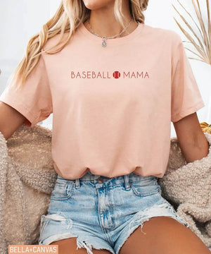 Person wearing heather peach Bella Canvas t-shirt with 'BASEBALL MAMA' text.