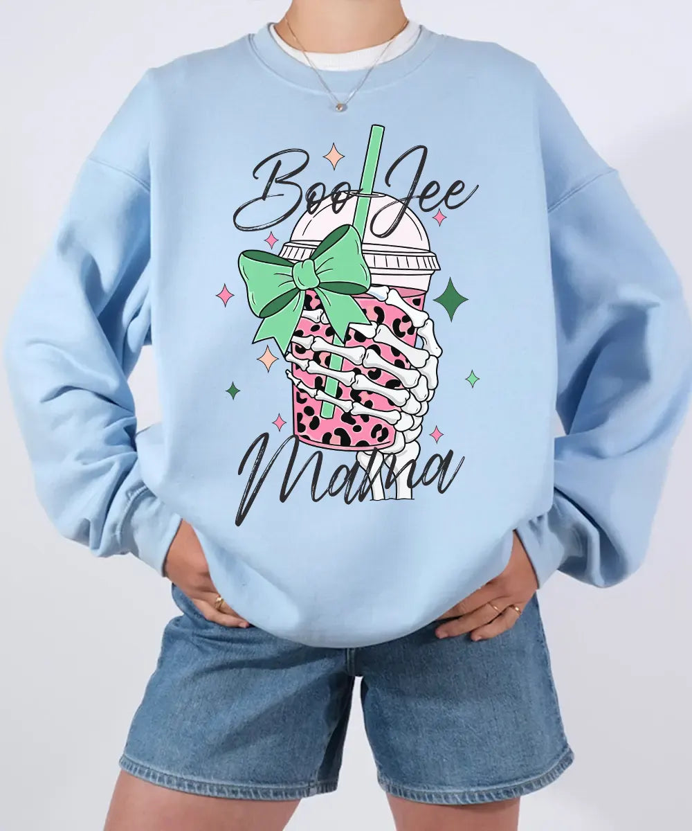 Person wearing light blue crewneck sweatshirt with a graphic design of a pink drink with a straw and bow, text 'Boo Jee Mama'.