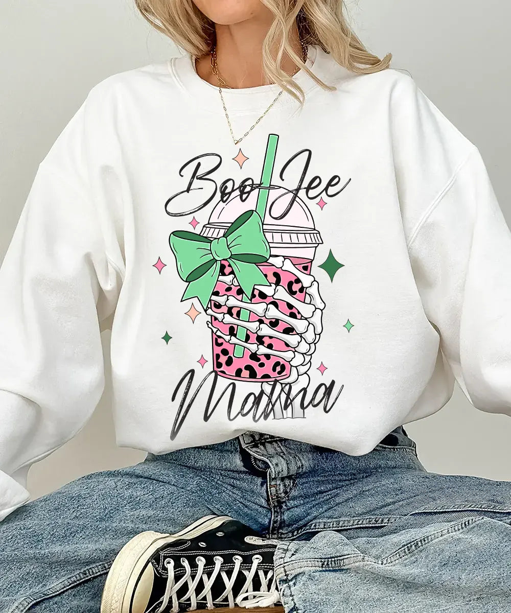 Person wearing white crewneck sweatshirt with a graphic design of a pink drink with a straw and bow, text 'Boo Jee Mama'.