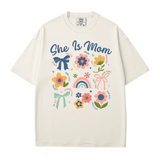 She Is Mom Comfort Colors® T-Shirt – Floral & Bow Inspirational Mom Shirt - Woven Mama